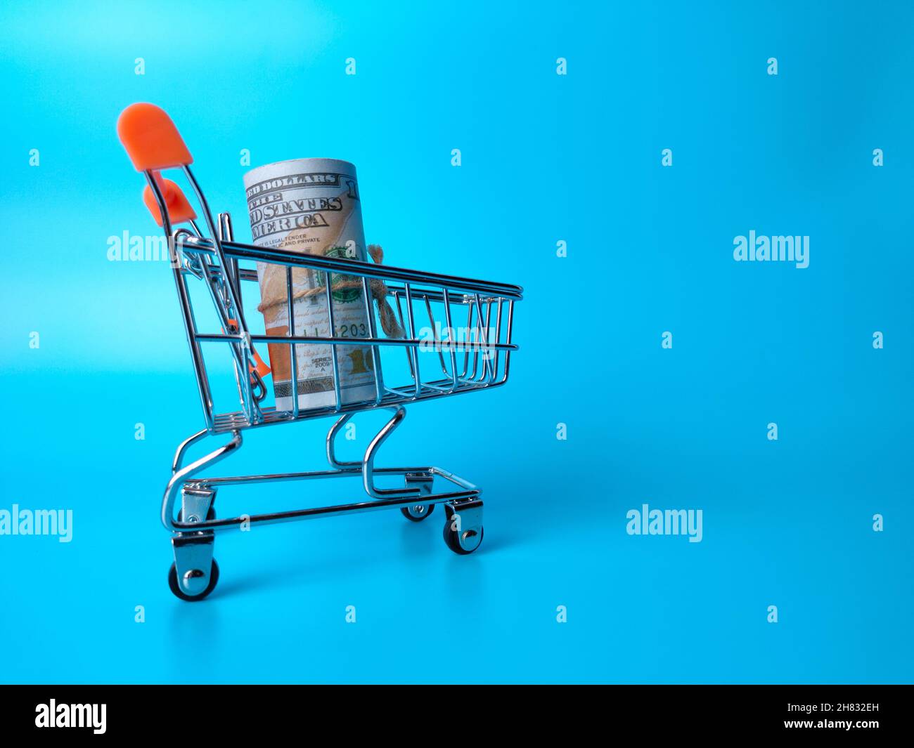 Banknotes inside shopping cart on a blue background with copy space ...