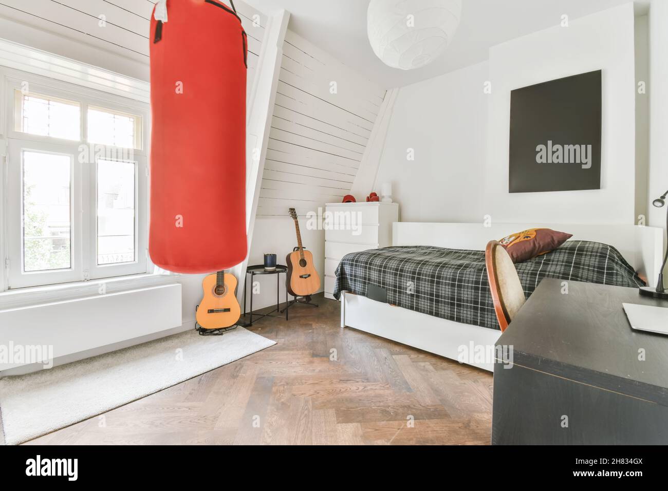 Stylish bedroom with a comfortable bed covered with a checkered duvet and a punching bag Stock Photo