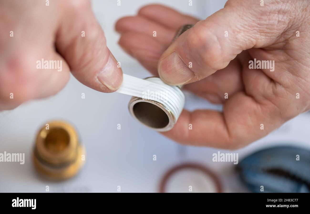 Plumber putting seal tape on a thread of a plumbing fitting Stock Photo