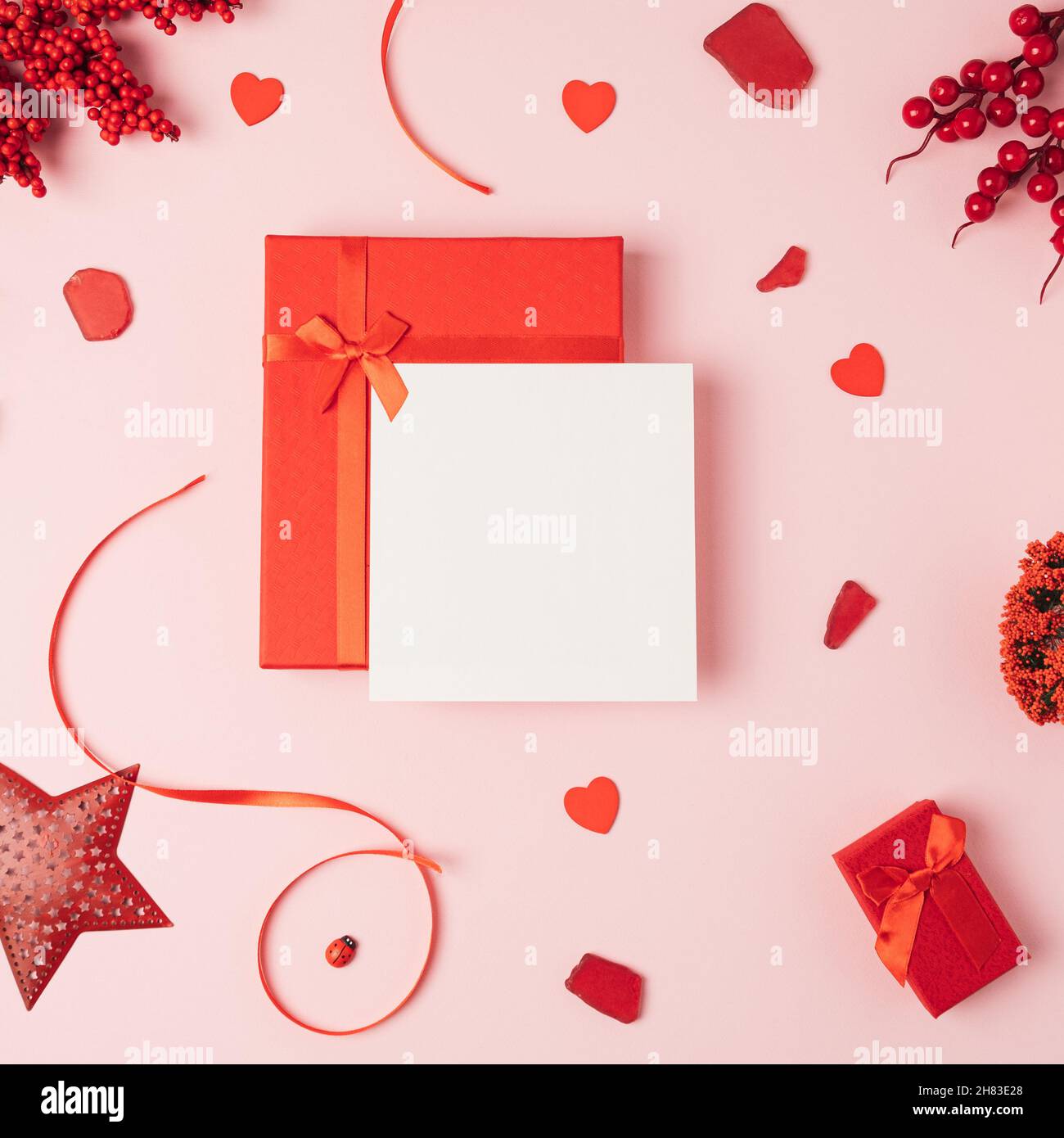 Red gift box with a card against light pink background. Love minimal ...