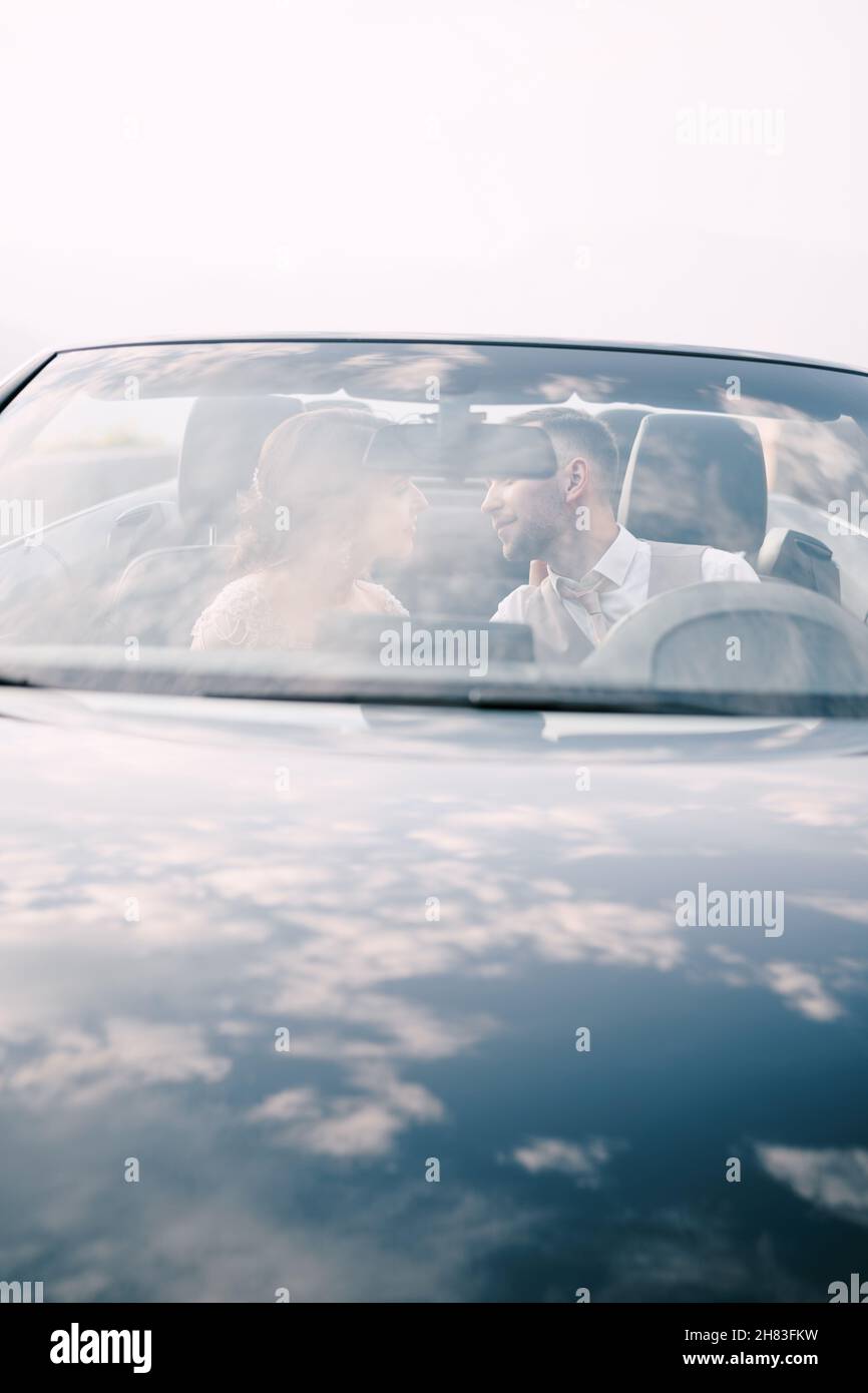 Bride and groom sit in the car and look at each other Stock Photo - Alamy