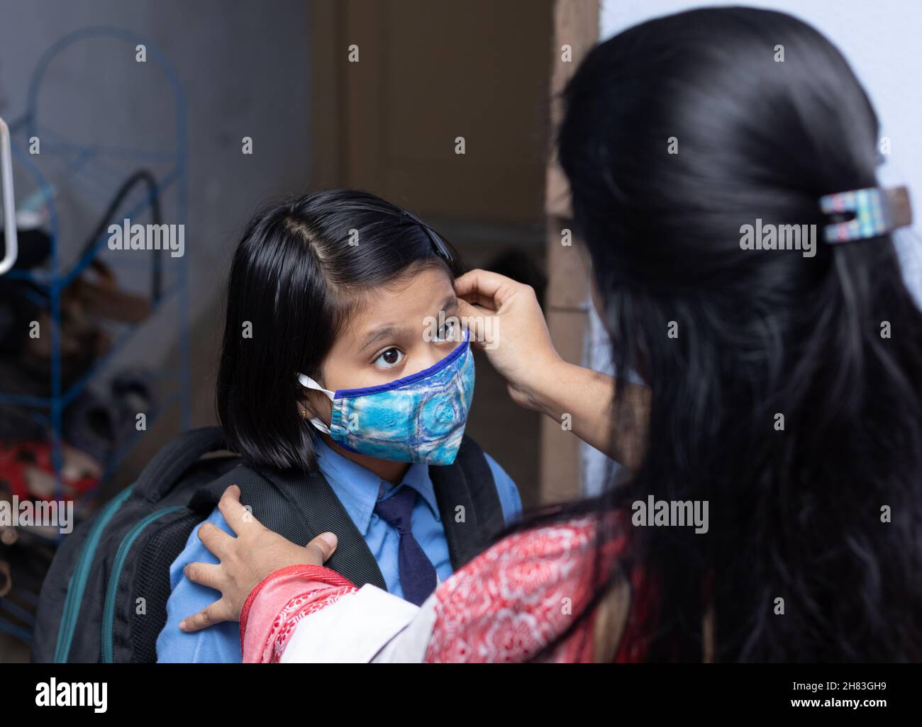 An Indian mother preparing her girl child with nose mask protection to send to school after pandemic Stock Photo