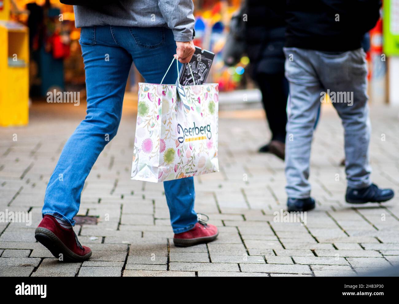 Oldenburg, Germany. 27th Nov, 2021. A woman walks through the city centre with a shopping bag. The Christmas business in the inner cities of Lower Saxony is threatened by a severe Corona dent this year as well. In view of the rapidly rising infection figures, the state government is also considering stricter requirements for retailers, for example in the form of mandatory testing. Credit: Hauke-Christian Dittrich/dpa/Alamy Live News Stock Photo