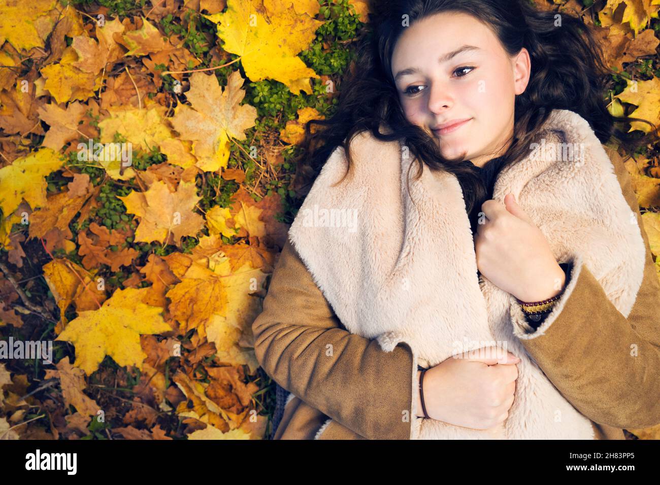 Young beautiful female in autumn with many benches leaves Stock Photo