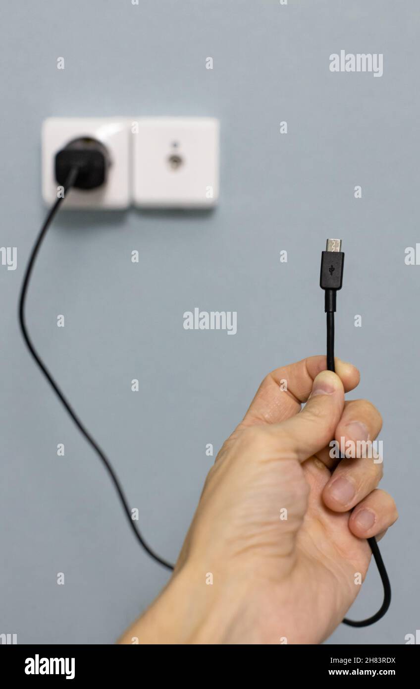 micro usb wire in hand against the background of the power supply. High quality photo Stock Photo