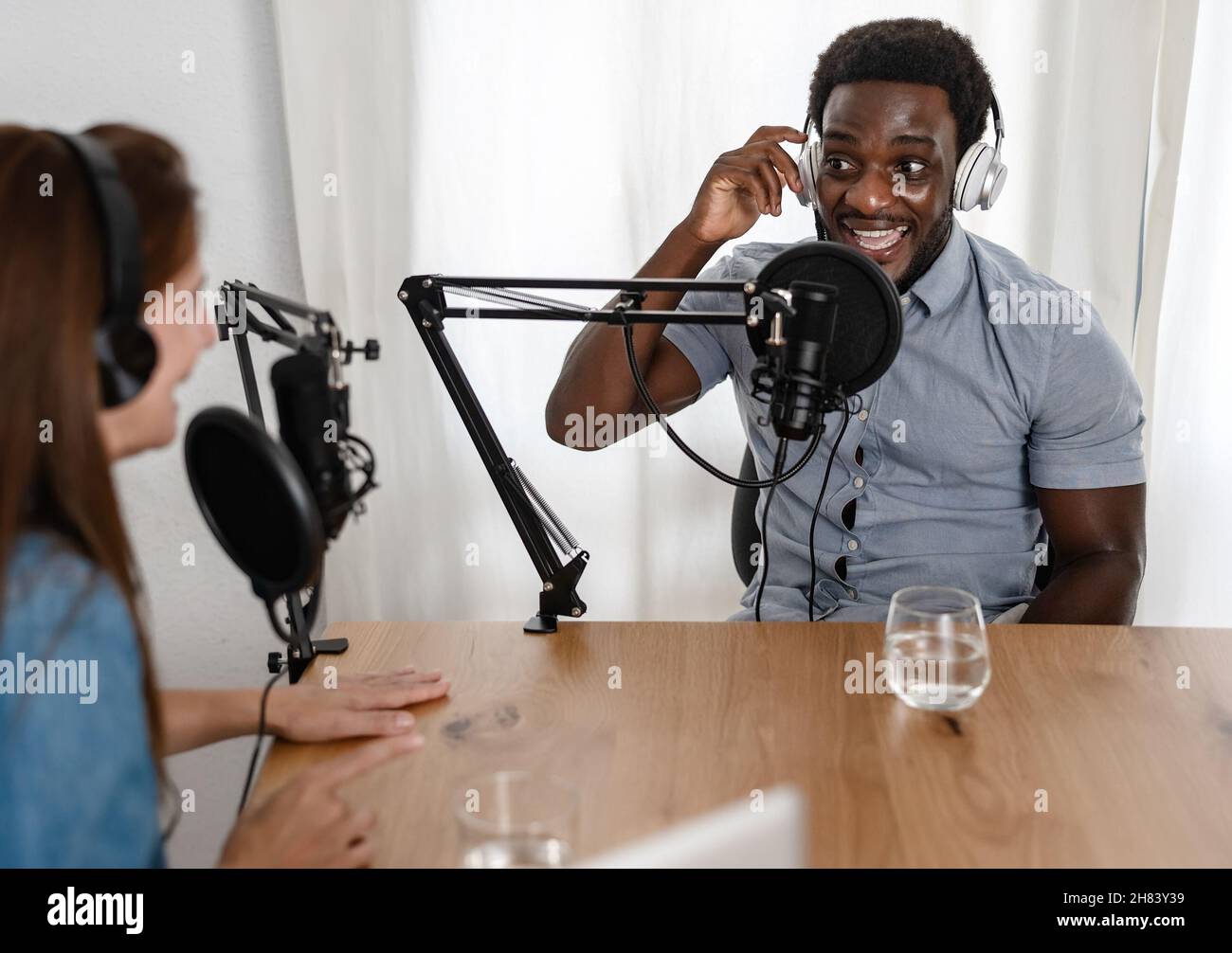 Multiracial people recording a podcast using microphone and headphones from home studio Stock Photo