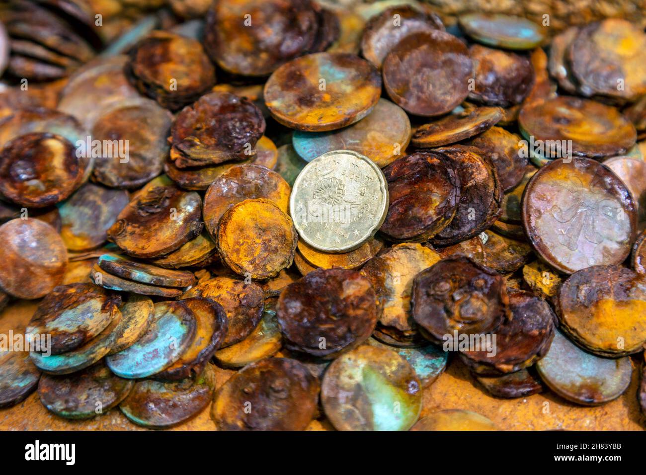 Corroded coins left at cross commemorating death of David Wordsworth Watson who fell from Carn Mellyn cliffs in 1873 near Lamorna Cove, Cornwall, UK Stock Photo