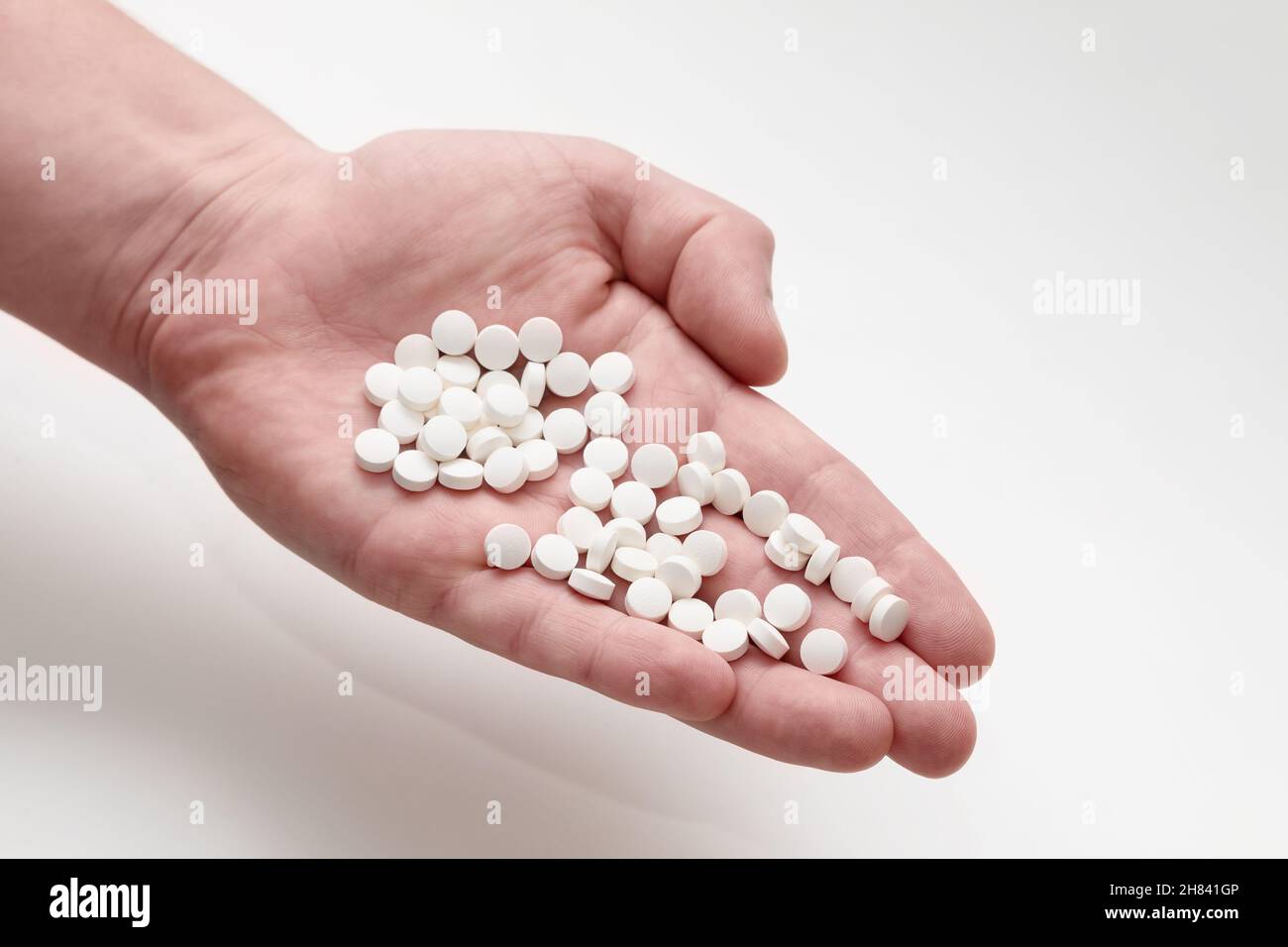 A lot of white round pills in a hand. Vitamin pills. Stock Photo