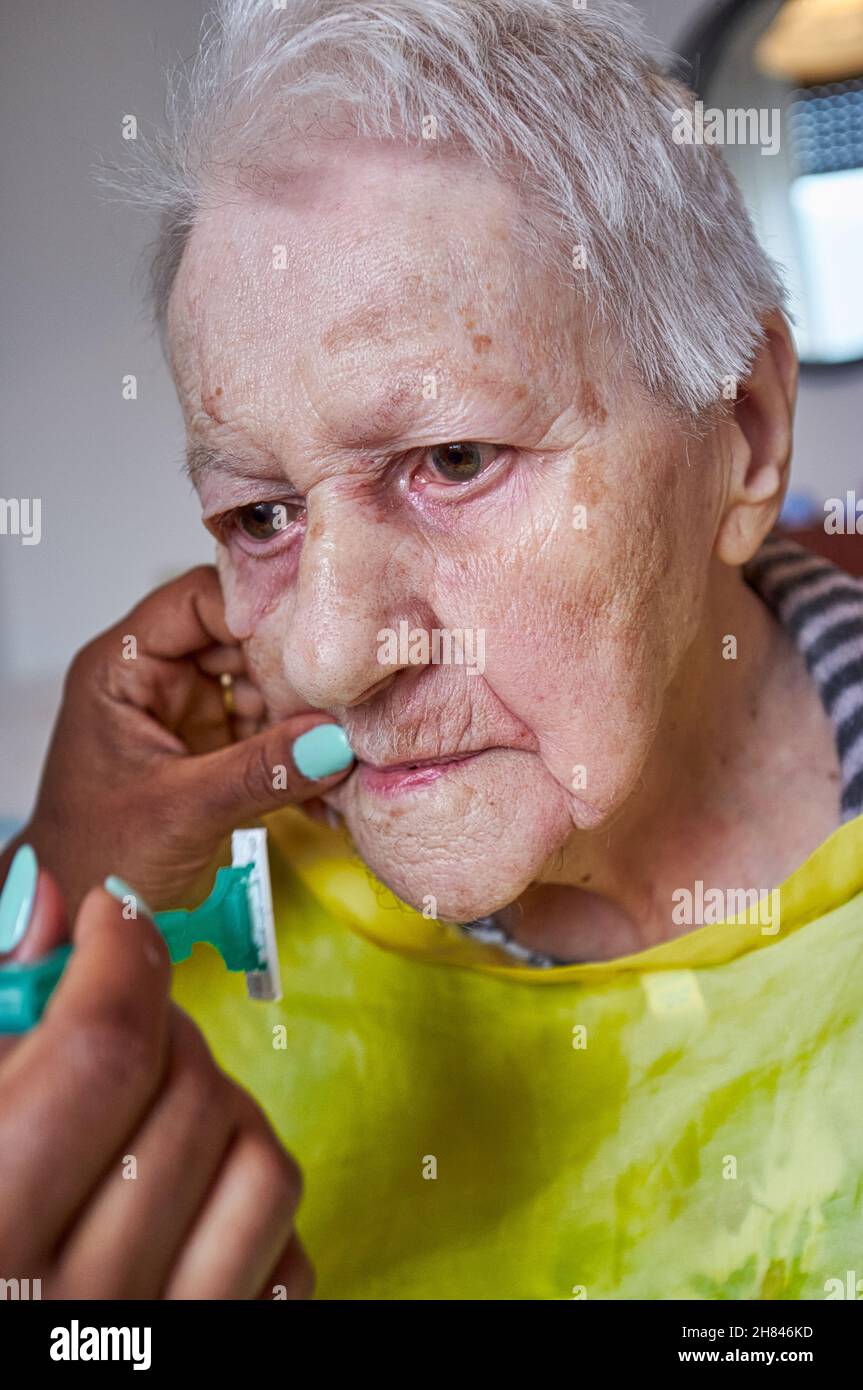 elderly woman receiving facial hair removal from african american
