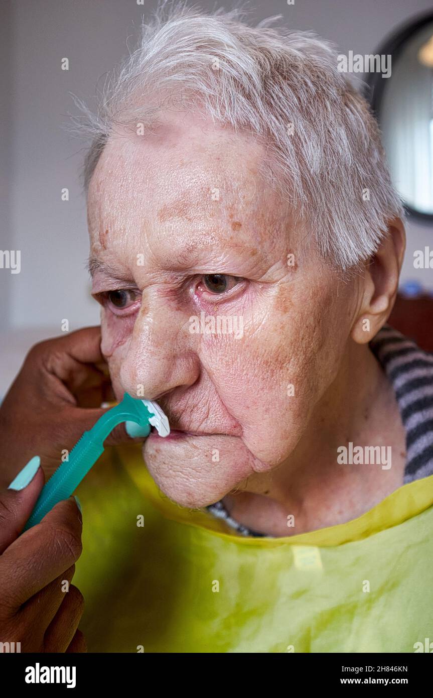 elderly woman receiving facial hair removal from african american