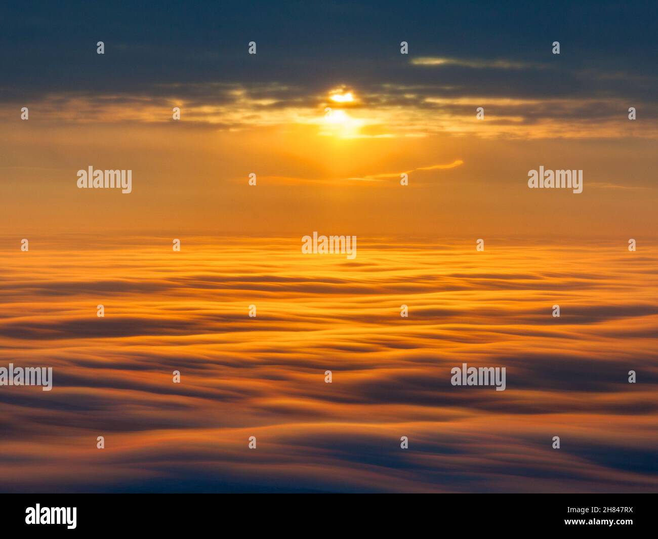 Aerial view of a cloudy sunset while flying above the clouds Stock ...