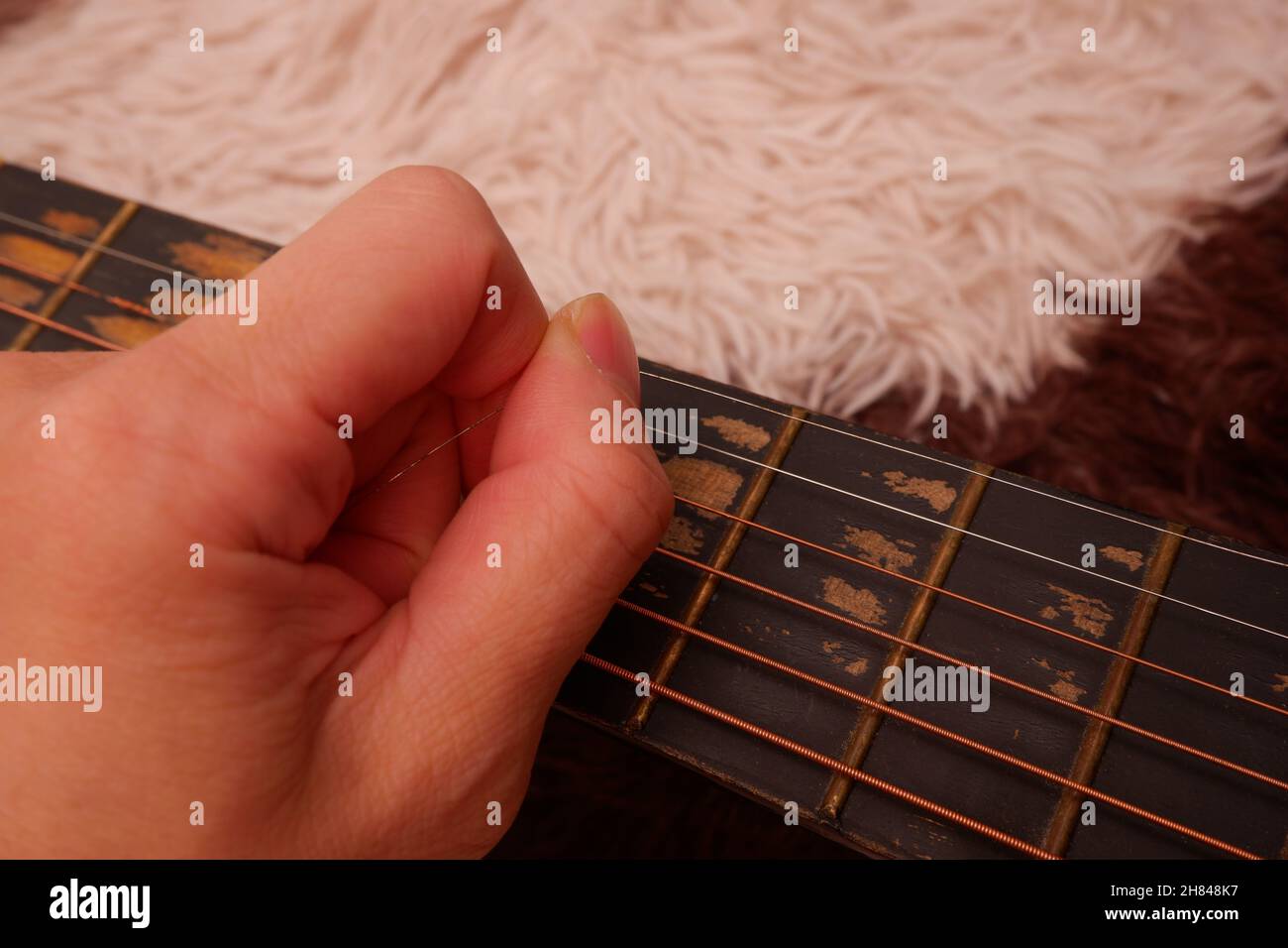 Repair a broken guitar by reconnecting the metal string Stock Photo Alamy