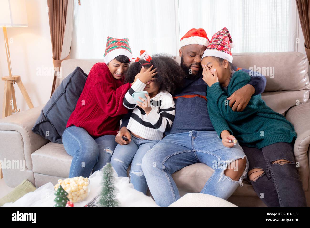 Happy African family sitting on couch watching TV with horror movie in ...