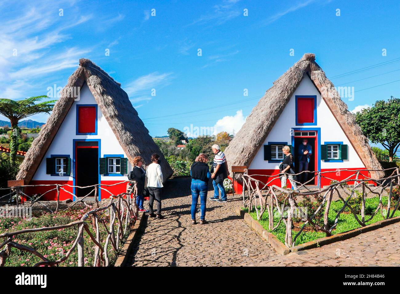 Tourists visiting the famous Santana Houses, the traditional triangular houses, typical of the island of Madeira, in Portugal, Europe. Stock Photo