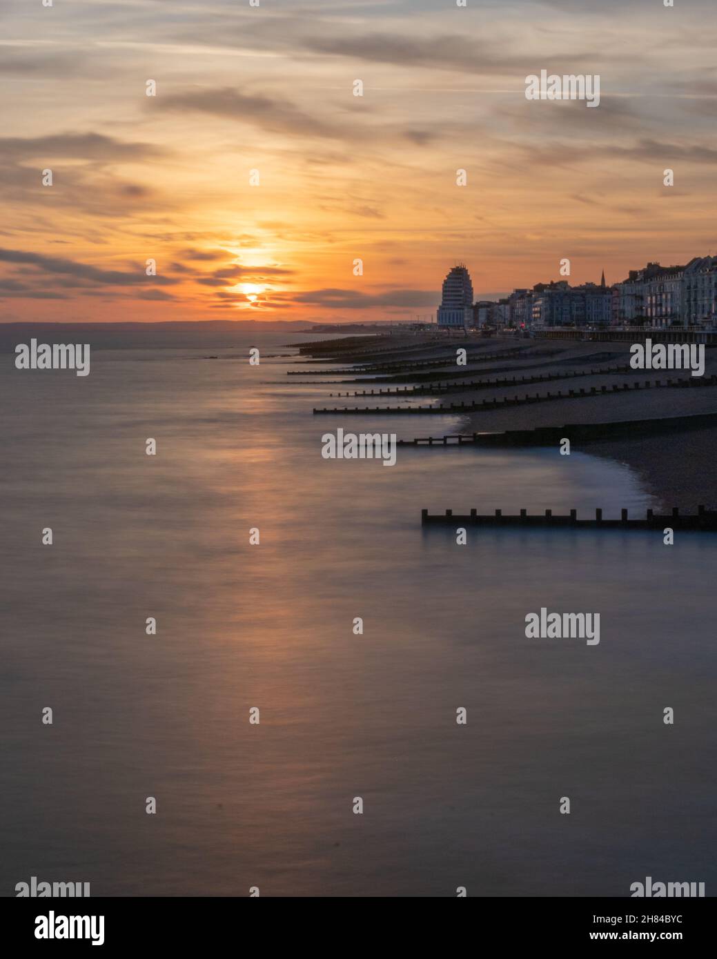 Sunset and golden hour on Hastings Pier, England, Uk looking out towards Eastbourne with the sea and the groynes in the foreground.Promenade Stock Photo