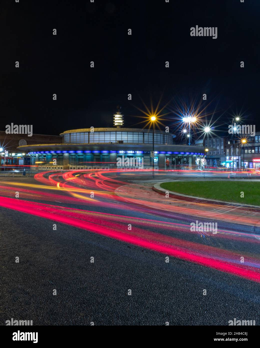 A long exposure night shot showing the cars travelling round the traffic island at Southgate tube station on the London underground piccadilly line Stock Photo