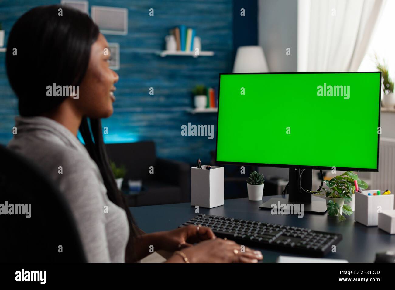 Young woman looking at monitor with horizontal green screen, working