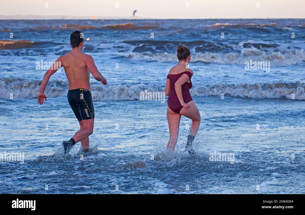 Portobello, Edinburgh, Scotland, UK. 27th November 2021. Temperature of 2 degrees and large waves from the remnants of Storm Arwen did not stop Edinburgh University students Elly and Fraser from having an exceptionally chilly afternoon dip in the Firth of Forth. Credit: Arch White Stock Photo