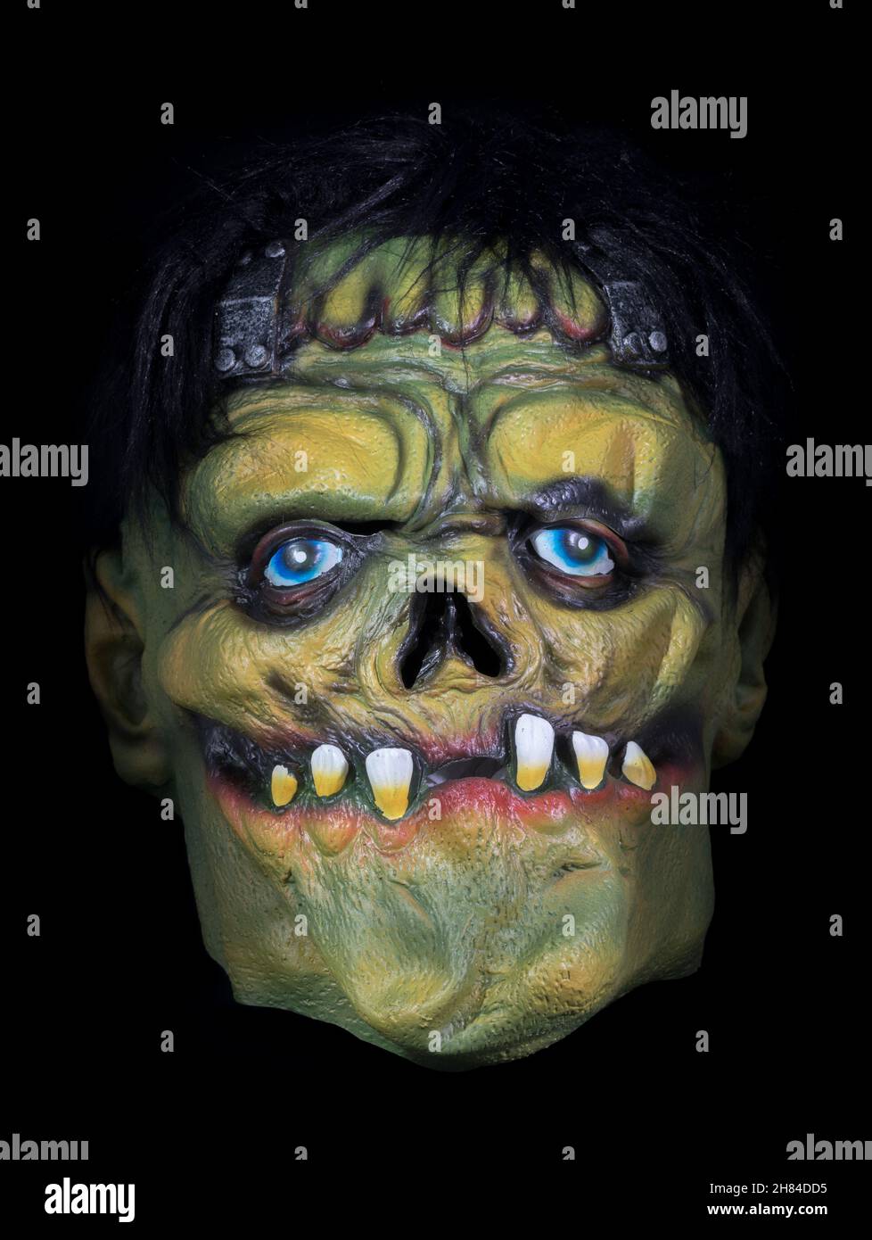 Green Face Monster with Wig Mask Isolated Against Black Background Stock Photo