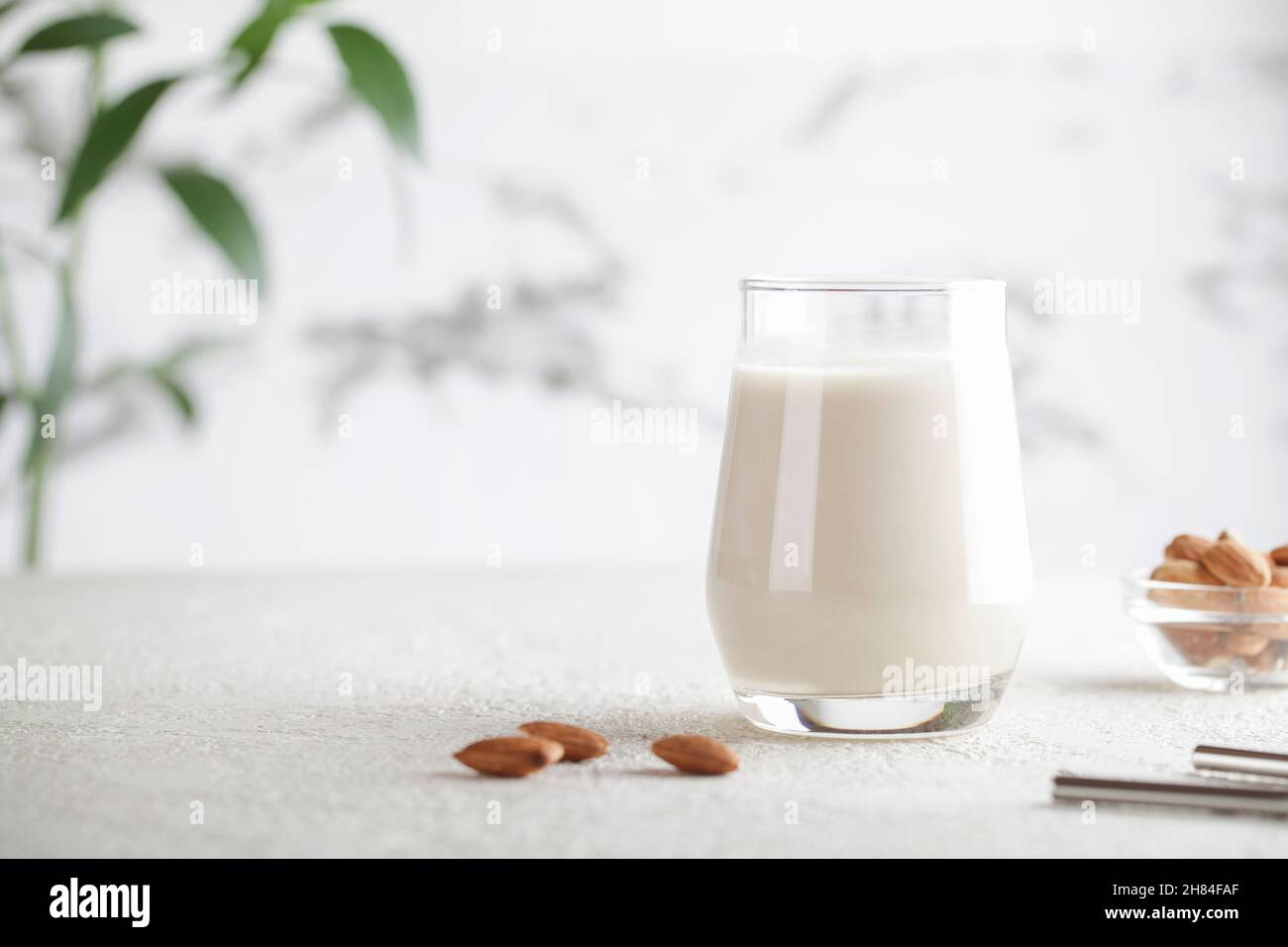 Vegan almond milk in glass with nuts on white background. Copy space. Healthy vegetarian food. selective focus. Non dairy alternative milk Stock Photo