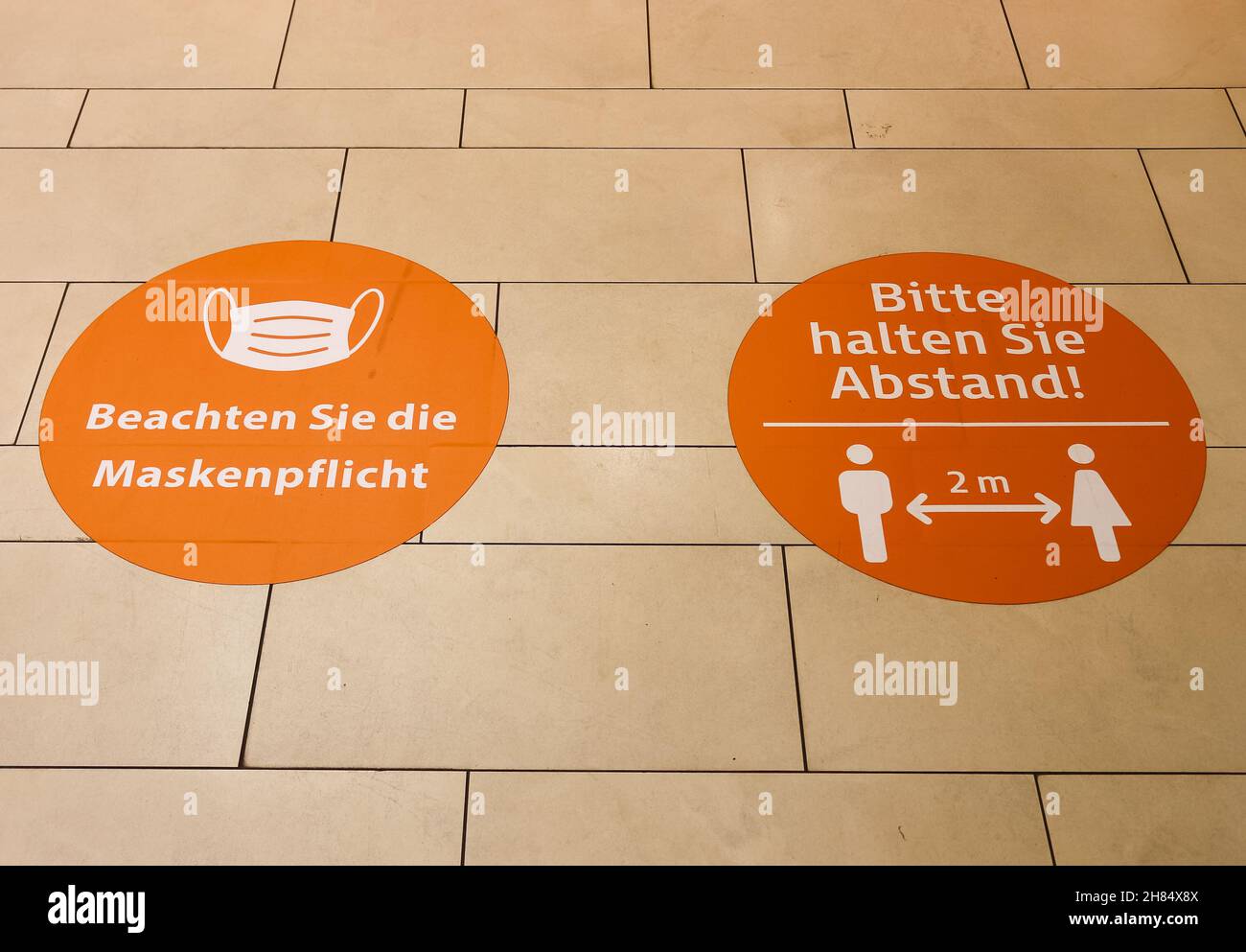 KIEL, GERMANY - Oct 30, 2021: The Corona mask obligation and distance signs on the floor of a shopping center in Germany Stock Photo
