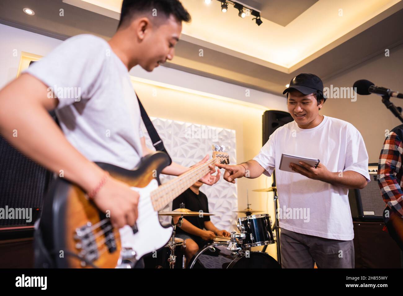 a male bassist plays an electric bass guitar with a vocalist during