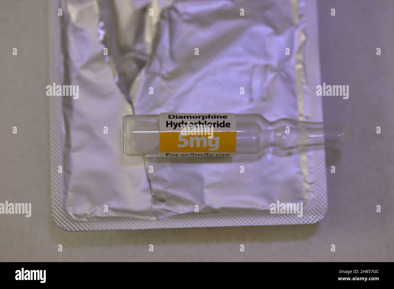 A glass ampoule  contianing 5mg of Diamorphine Hydrochloride (heroin) as a powder, on a packet of 5 other ampoules Stock Photo