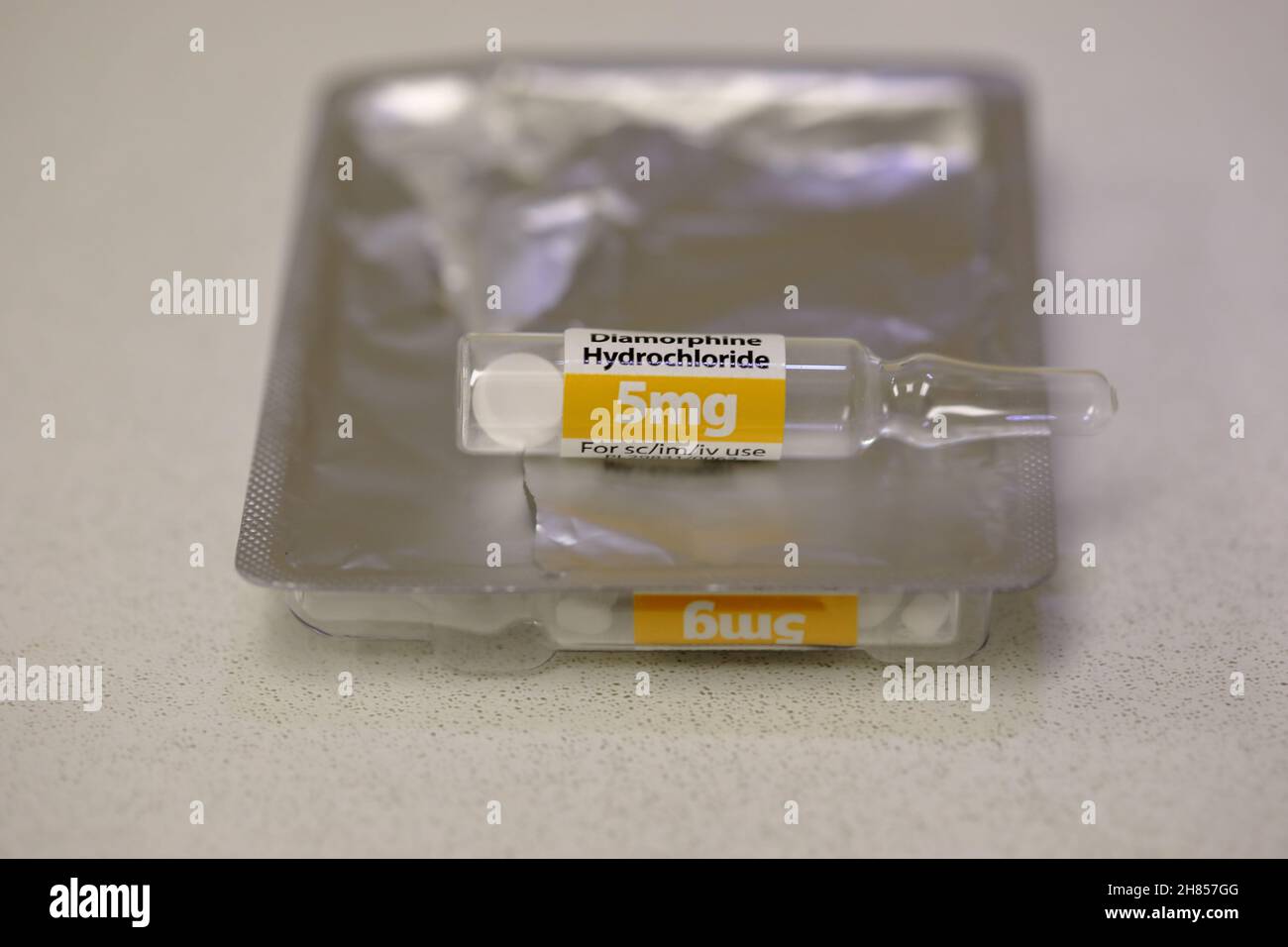 A glass ampoule  contianing 5mg of Diamorphine Hydrochloride as a powder, on a packet of 5 other ampoules Stock Photo