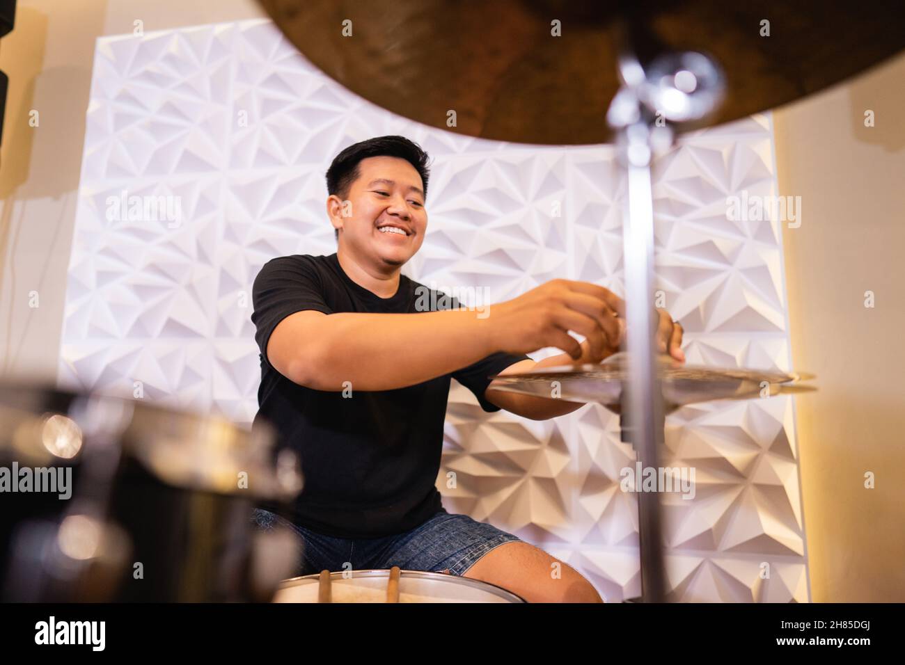 a drummer smiles while preparing hihat cymbals before being used Stock