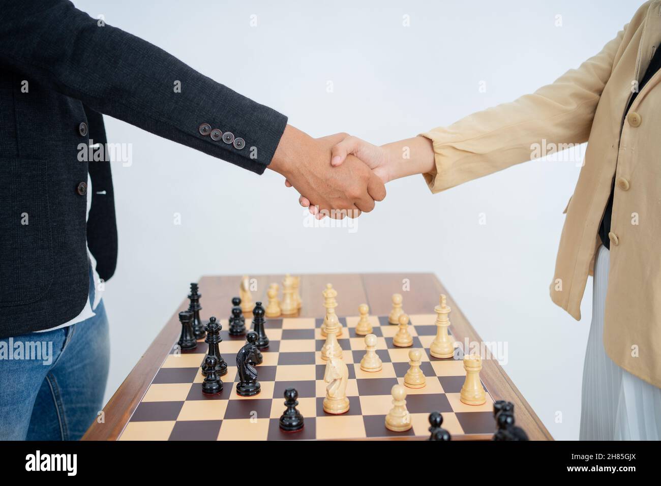 Male and female hands shaking hands over chess pieces Stock Photo