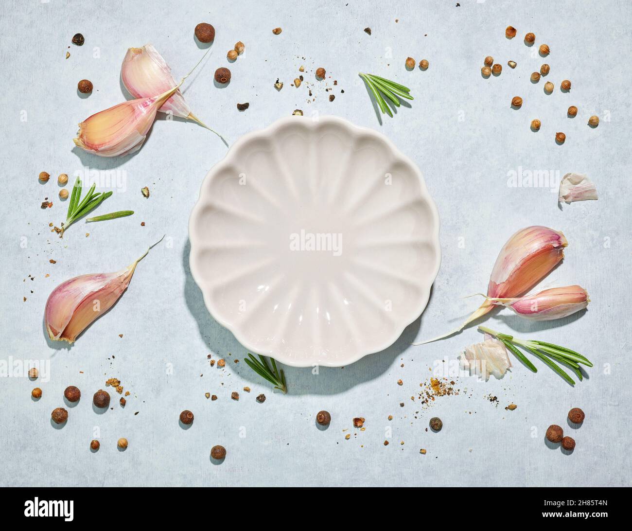 composition of decorative white plate and various spices on blue background, top view Stock Photo