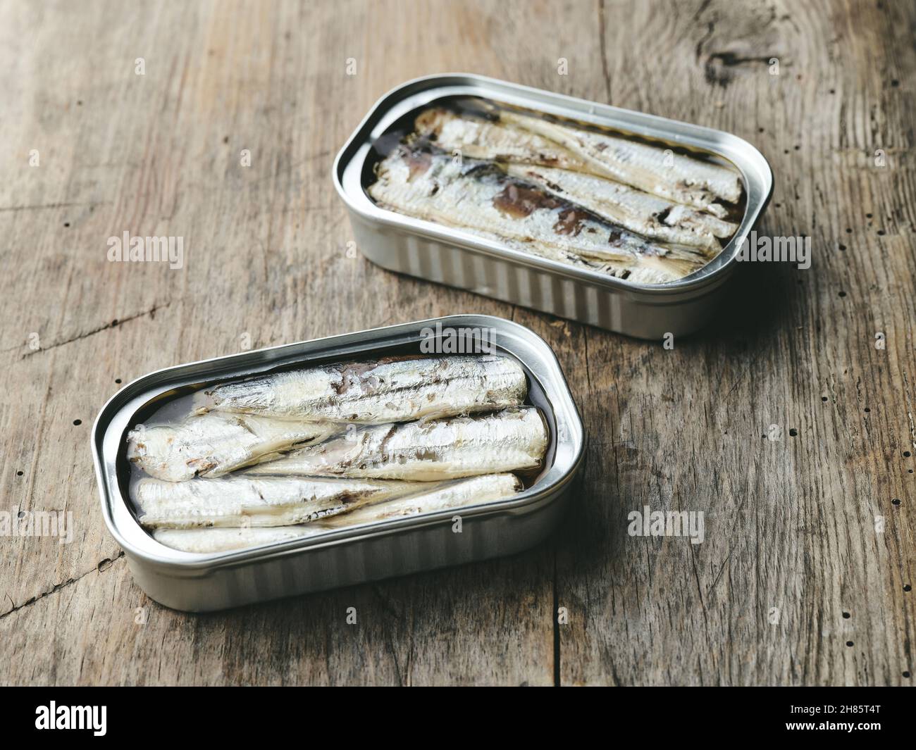 open sardines cans on rustic wooden kitchen table Stock Photo