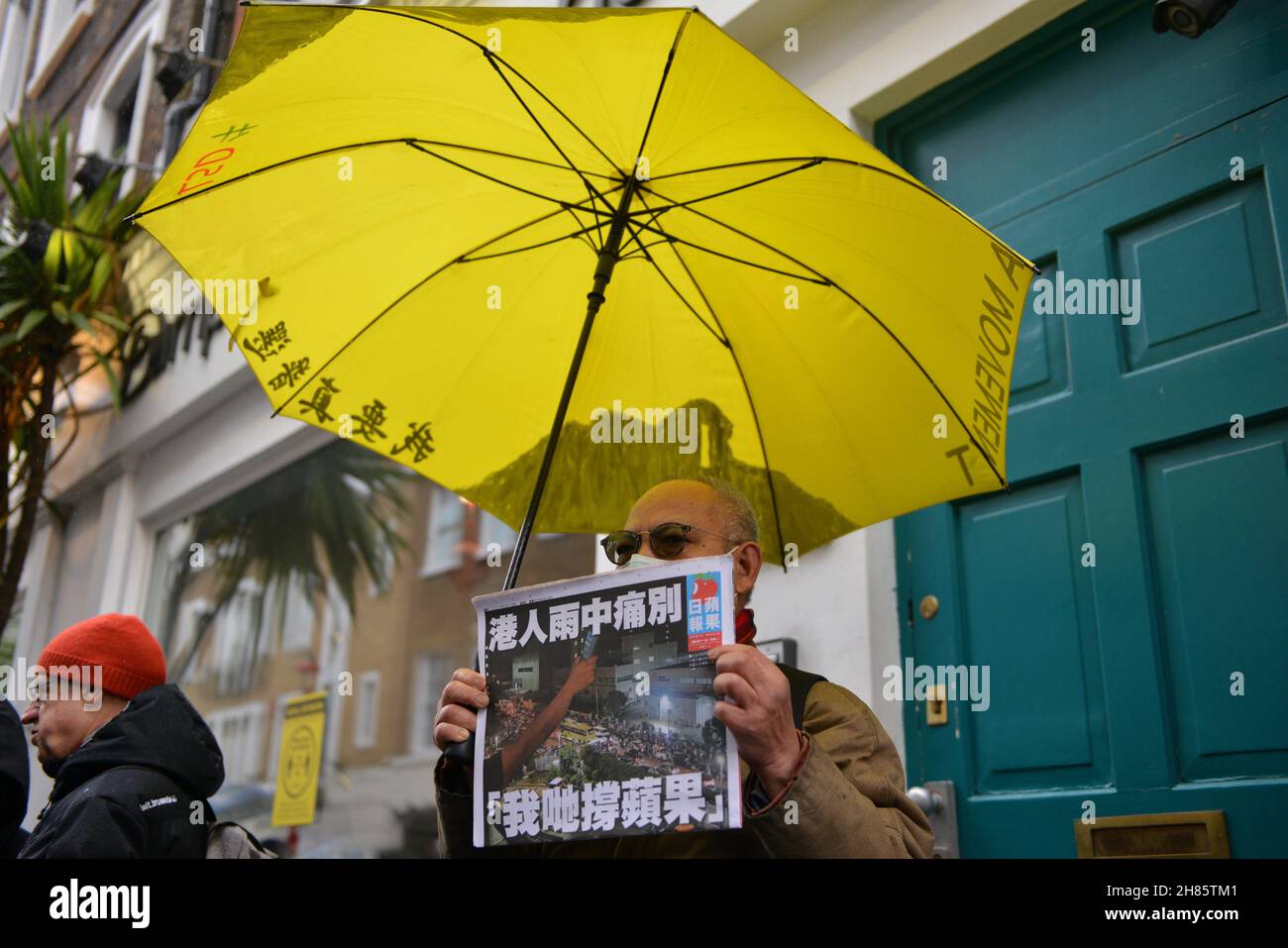 London, UK. 27th Nov, 2021. A pro Hong Kong democracy protester holds a apple daily newspaper and a yellow umbrella during the counter protest. Dozens of pro democracy, pro Hong Kong independence and anti CCP (Chinese Communist Party) protesters hosted a counter protest against the Stop Anti-Asian Hate rally 'against the new cold war' organized by the Chinese associations in the UK, in London's Chinatown. Credit: SOPA Images Limited/Alamy Live News Stock Photo