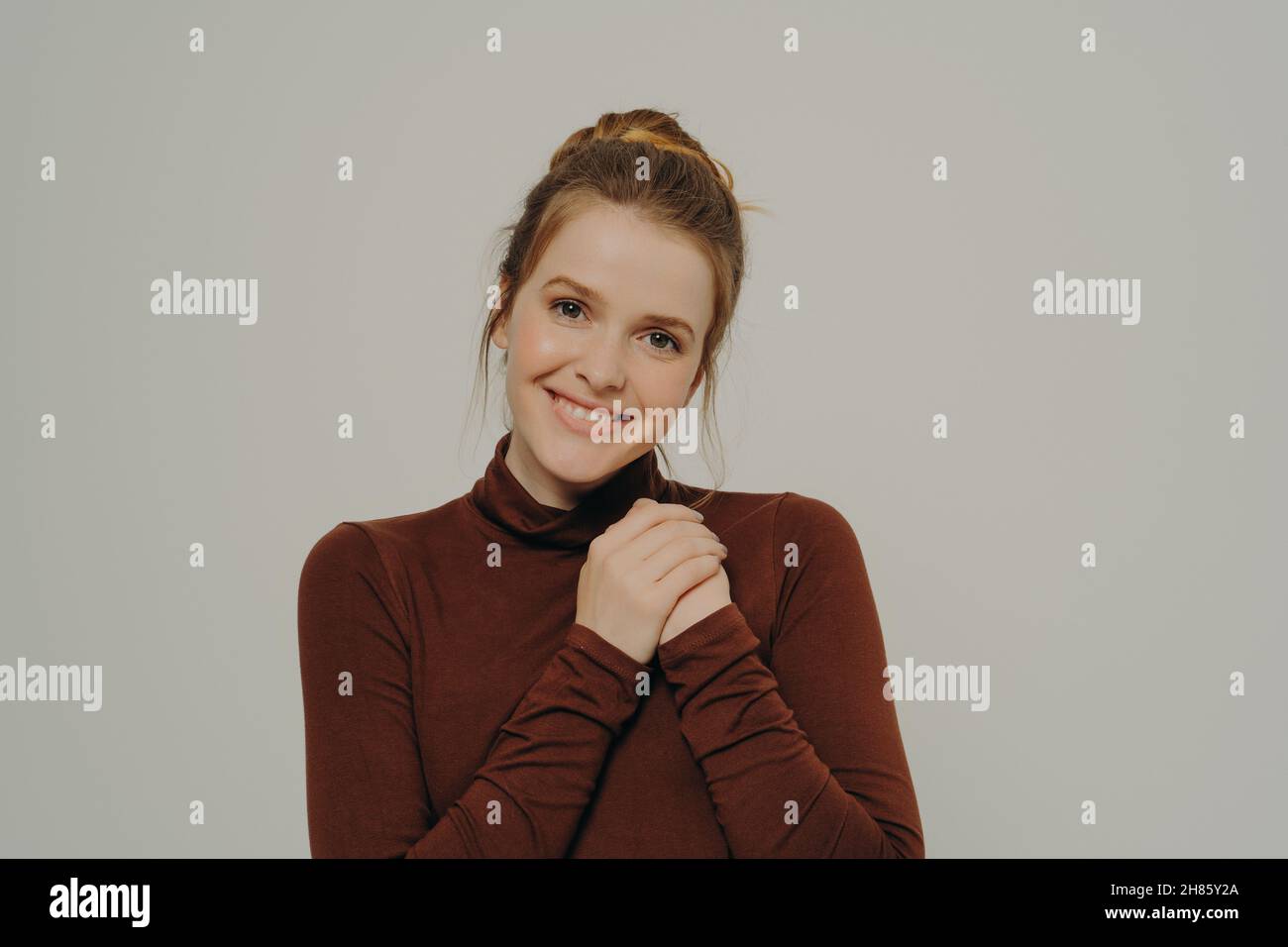 Grateful thankful young woman holding folded hands on chest, expressing gratitude and thankfulness Stock Photo