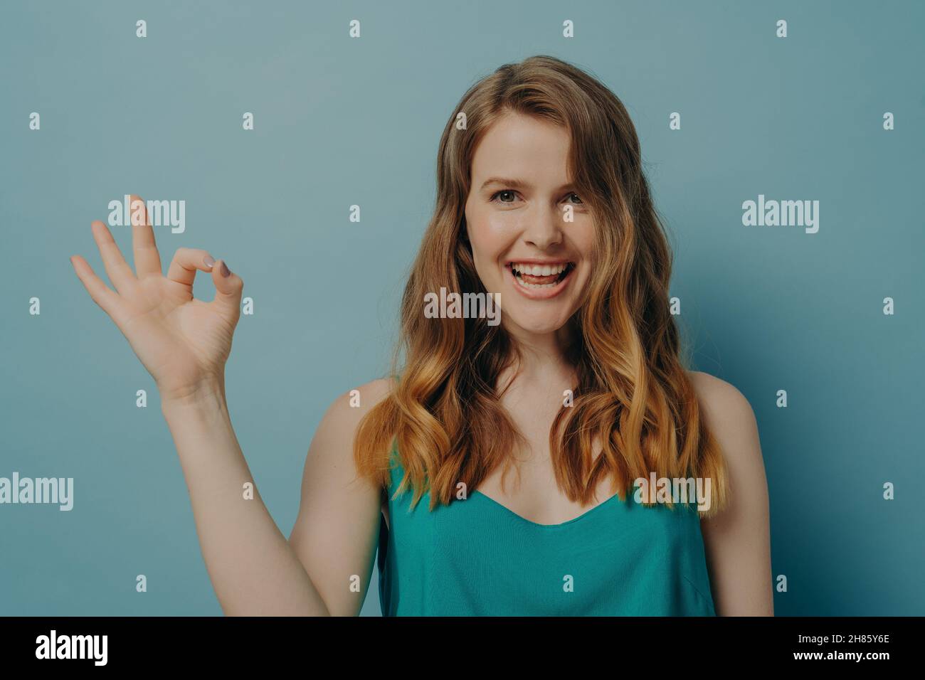 Happy young charming woman with showing ok sign with fingers and smiling at camera Stock Photo