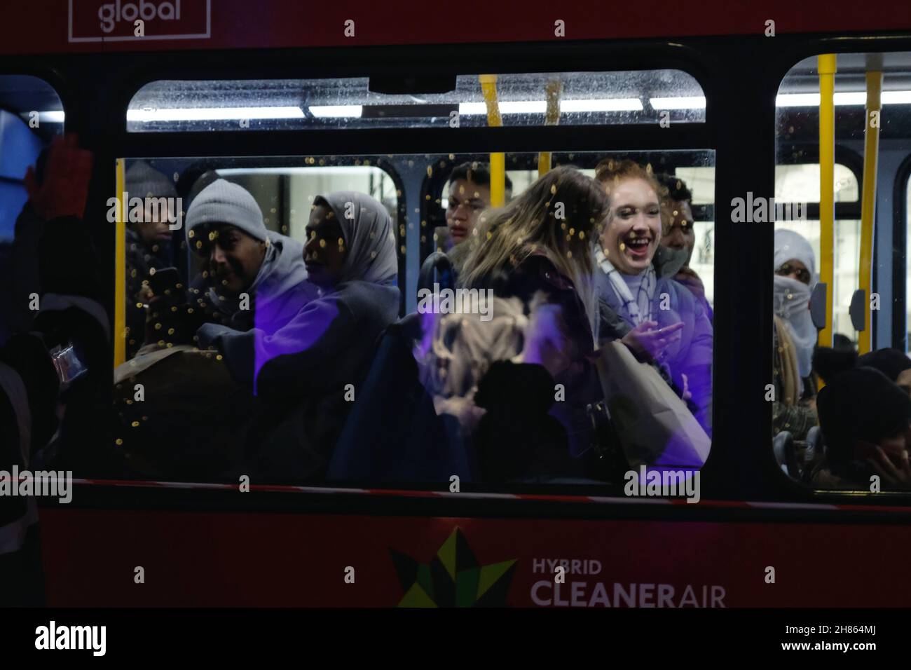 London, UK, 27th Nov, 2021. Bus passengers are seen reacting to the passing 'Reclaim the Night' march passing by. The annual women's-only event is held to protest all forms of male violence against women. Specifically during the Covid-19 lockdowns, women's charities became concerned with the increase in demand for services and UK police recorded a 7% rise in recorded domestic abuse crimes. This year also saw the murders of Sarah Everard and Sabina Nessa. Credit: Eleventh Hour Photography/Alamy Live News Stock Photo