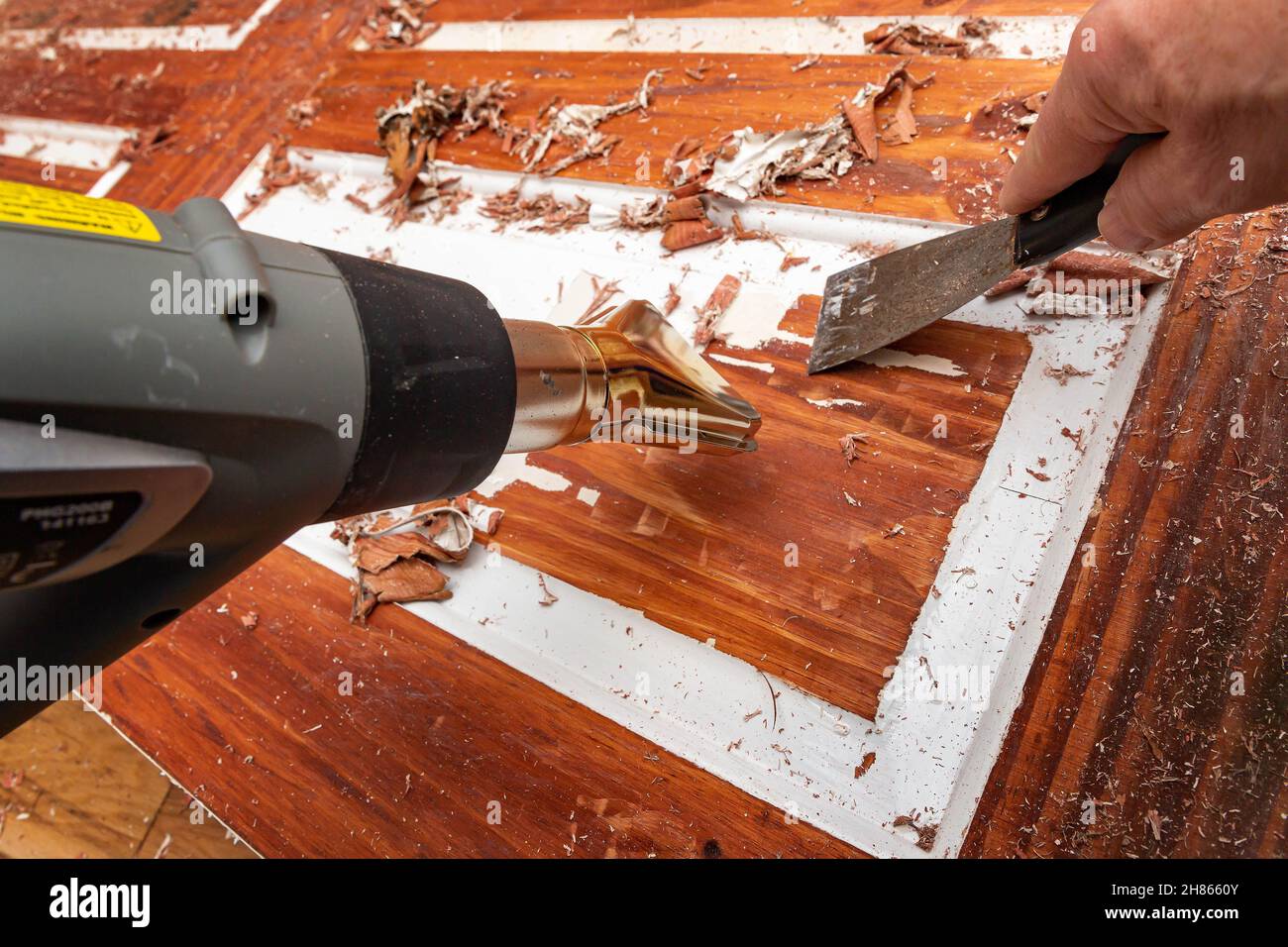 Stripping paint off a 6panel wooden door using a heat gun and scraper Stock Photo Alamy