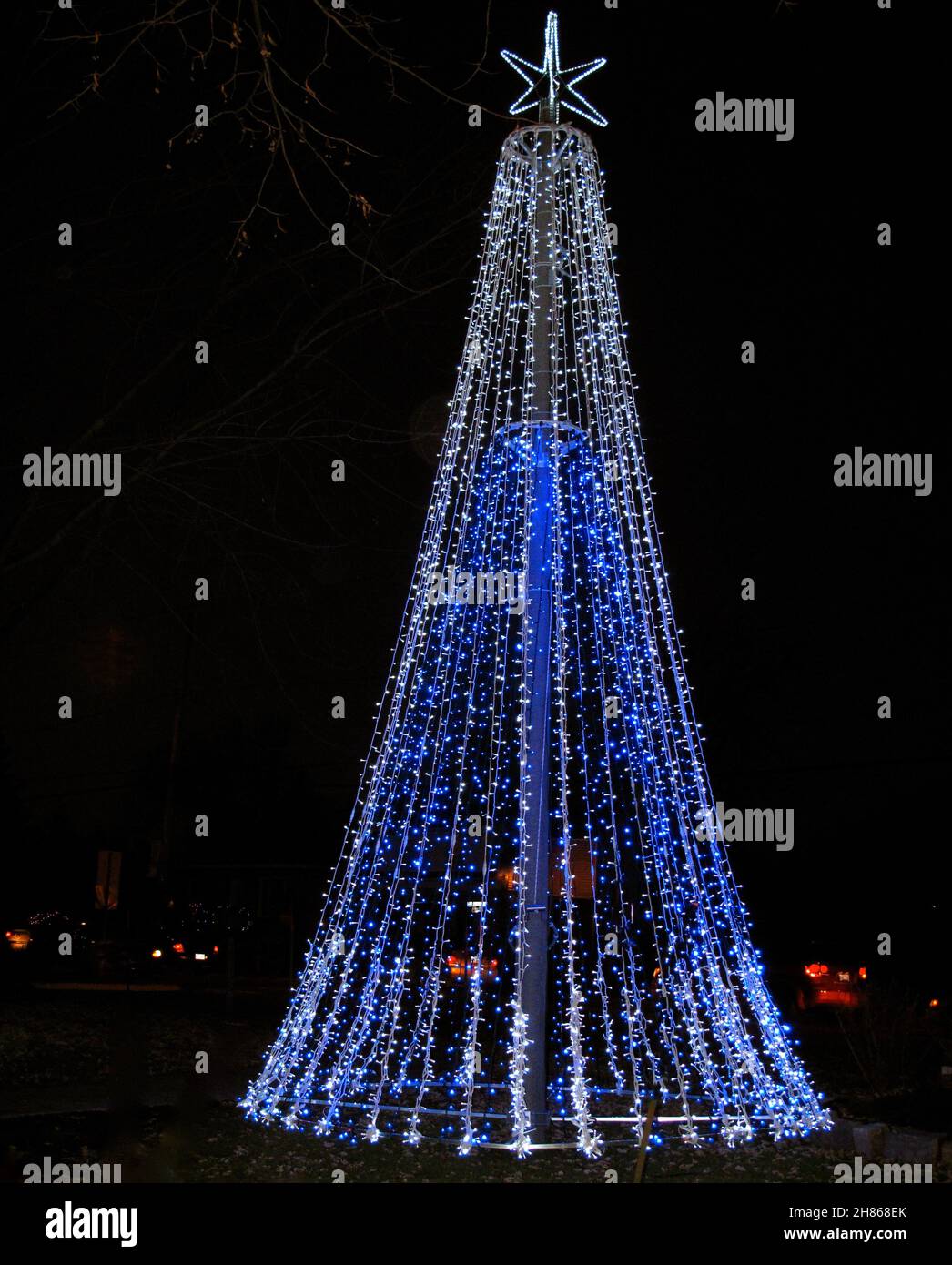 Tall outdoor Christmas tree formed with blue and white string of lights Stock Photo