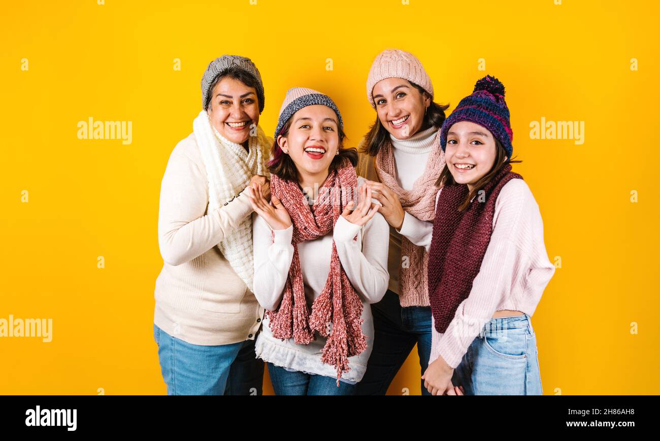 Winter portrait of happy latin family three generations of hispanic women on yellow background