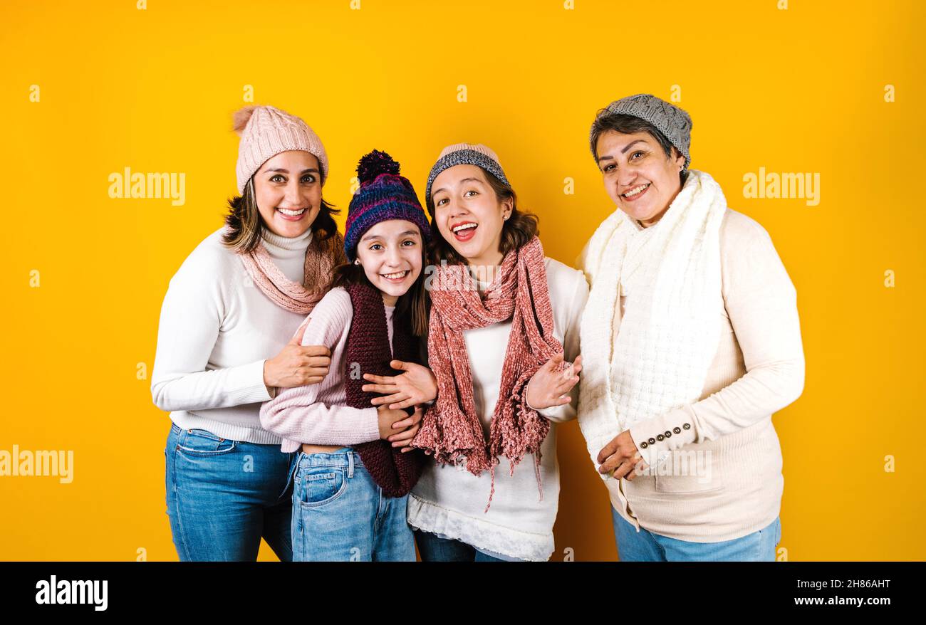 Winter portrait of happy latin family three generations of hispanic women on yellow background