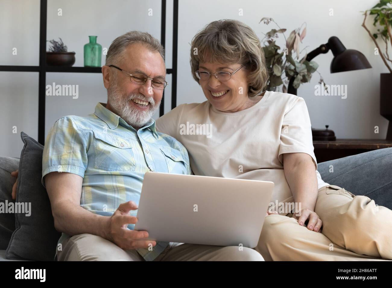 Happy mature married couple using laptop on sofa Stock Photo