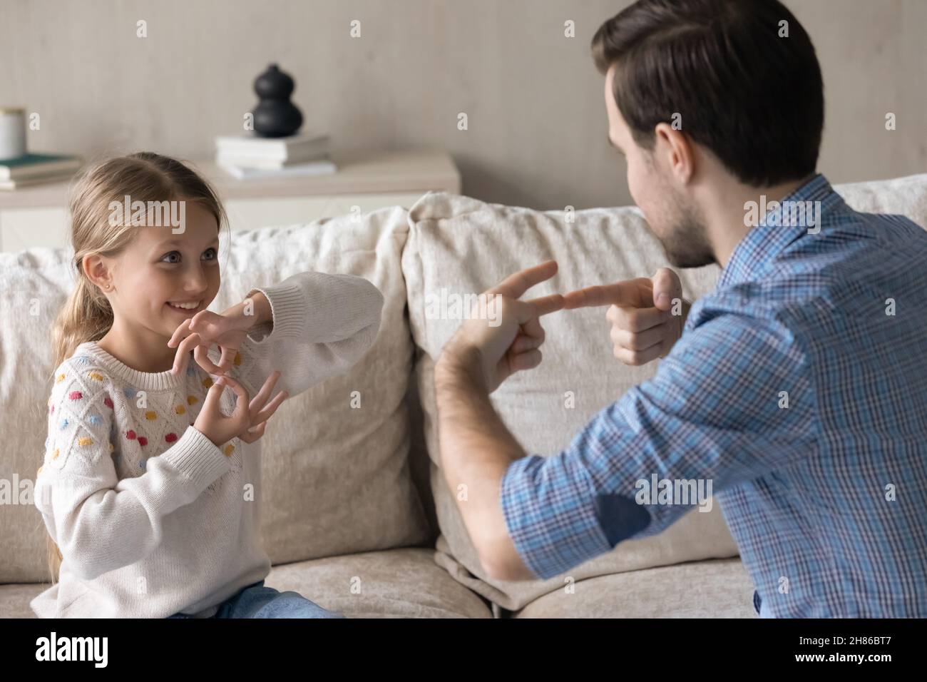 Happy adorable small kid using sign language, communicating with father. Stock Photo