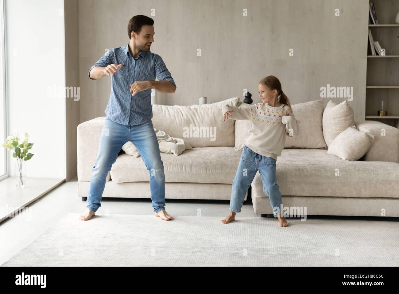 Caring happy young father dancing with adorable little daughter. Stock Photo
