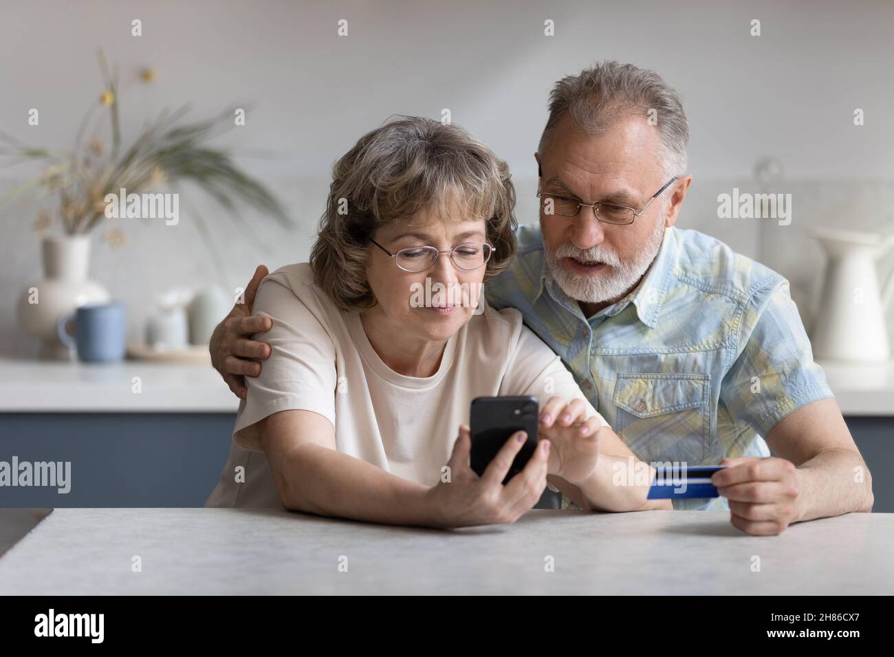 Serious older married couple shopping on internet stores Stock Photo