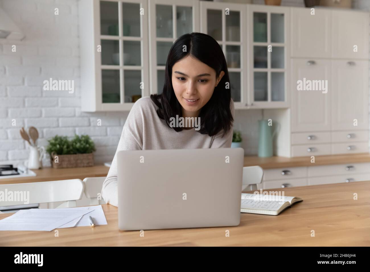 Young Asian woman sit at table working using laptop Stock Photo