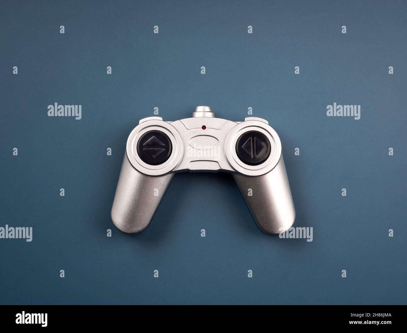 Silver retro style radio remote control for a toy isolated on blue background, top view. Game controller  joystick, flat lay, minimal style. Stock Photo