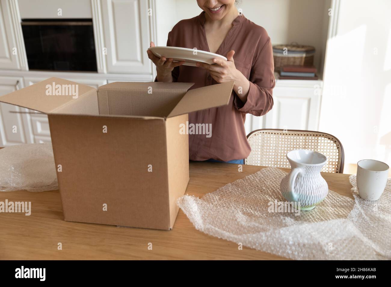 Smiling young indian woman unpacking ware from carton box. Stock Photo