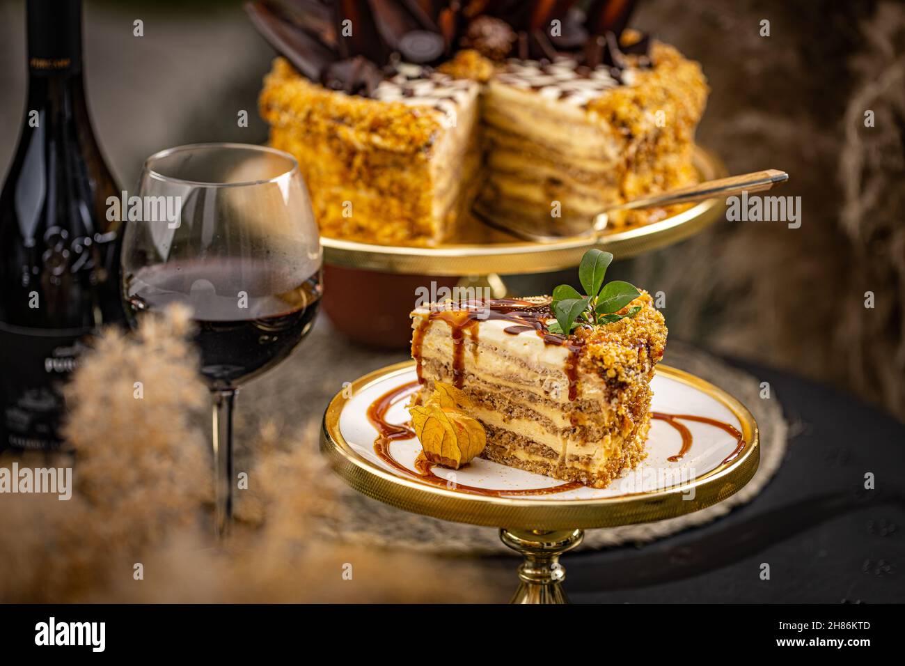Slice of layered walnut cake served with a glass of wine Stock Photo