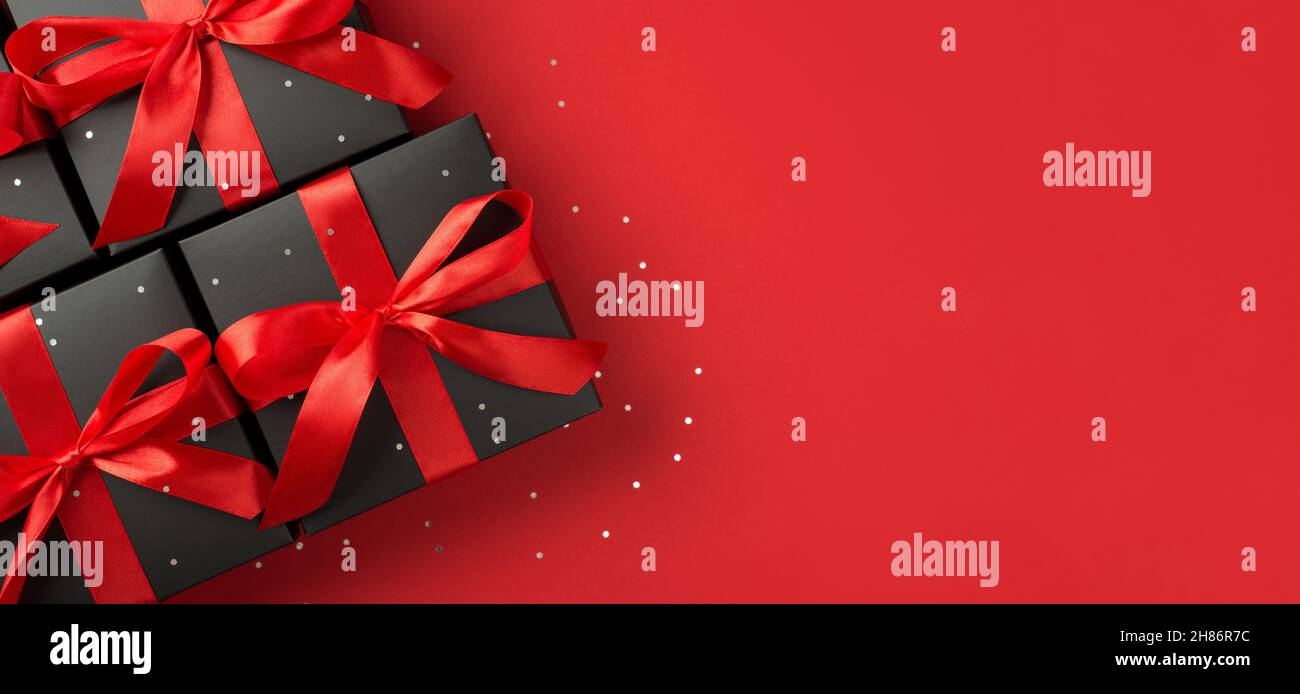 Top view photo of black gift boxes with red ribbon bow and confetti on ...