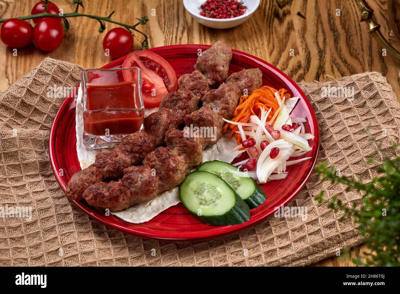 Tasty lula kebab on the plate on a wooden table. Chopped meat on wooden skewers, grilled. Eastern cuisine. Stock Photo